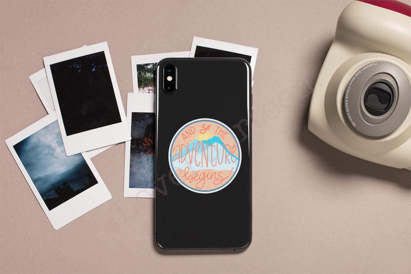 polaroid camera and smartphone with waterproof die cut sticker saying "and so the adventure begins" 